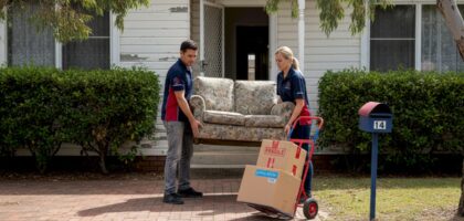 Removalists moving sofa out suburban house