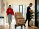 Couple moving boxes in Melbourne apartment hallway