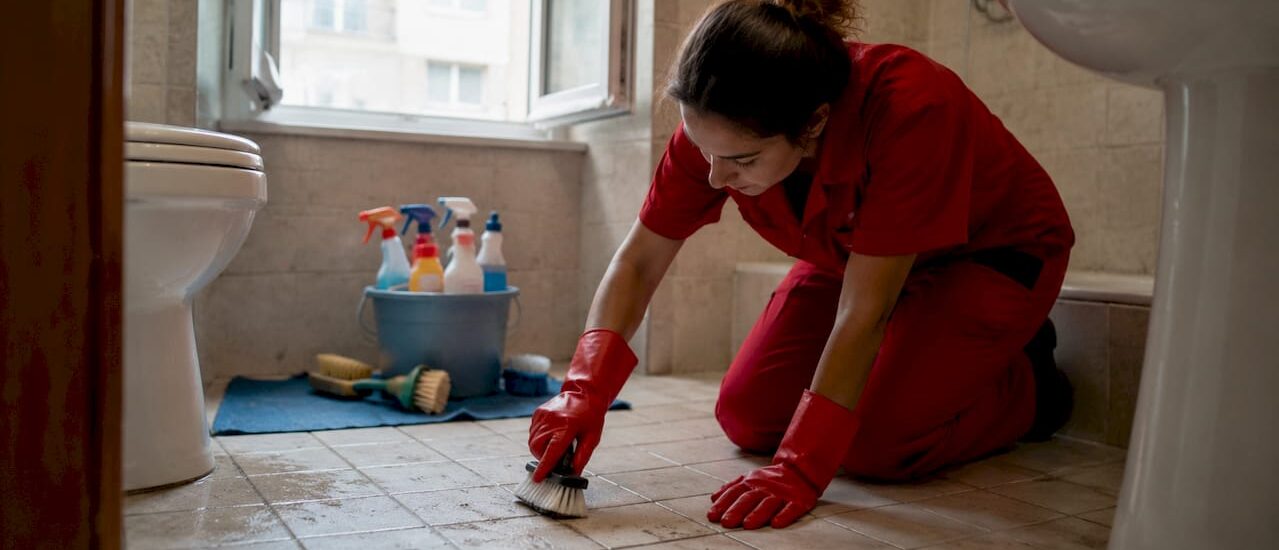 Professional cleaner scrubbing bathroom grout