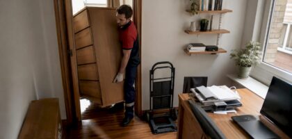 Mover carrying heavy dresser down stairs