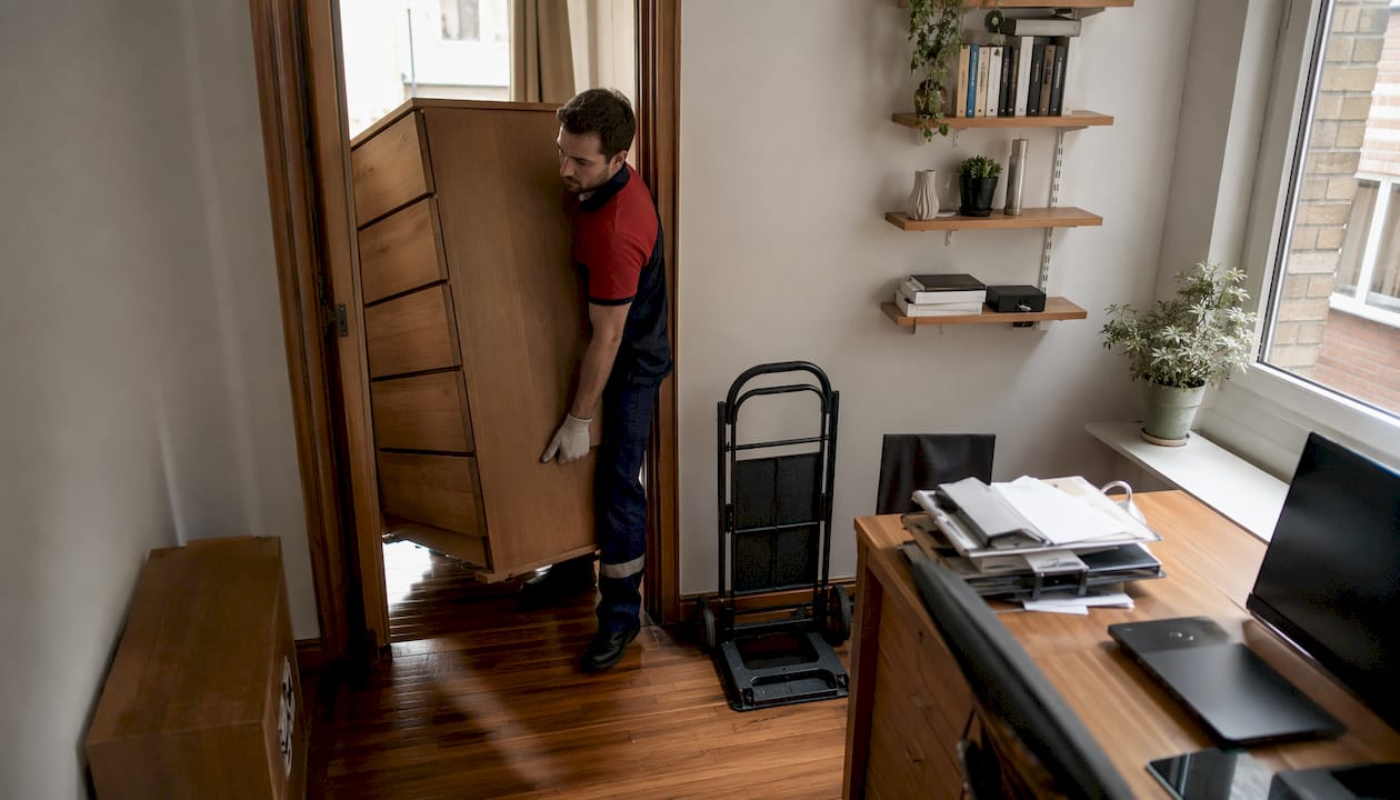 Mover carrying heavy dresser down stairs