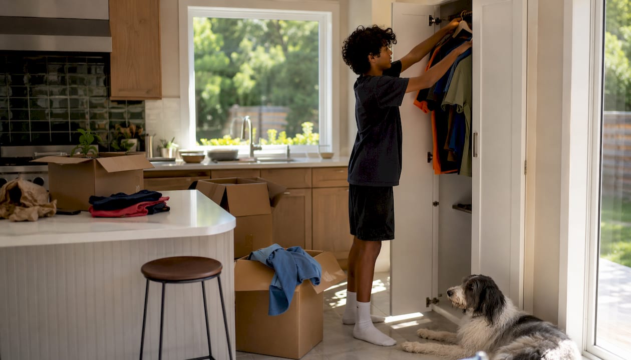 Teen organizing clothes in new bedroom