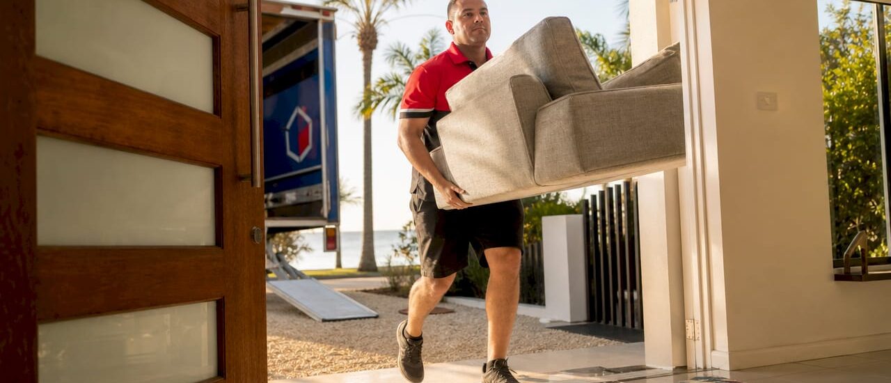Furniture delivery worker bringing sofa inside home