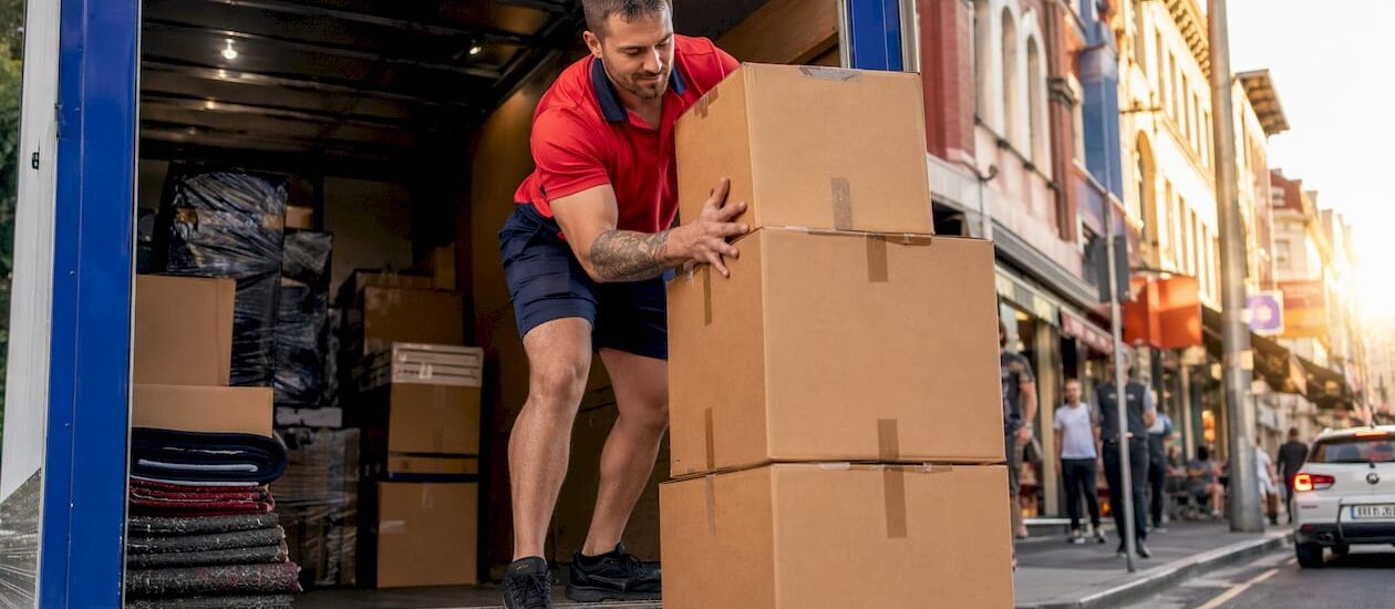 Mover loading boxes into removalist truck outside house