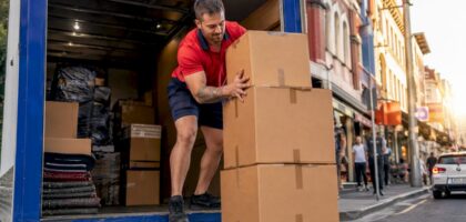 Mover loading boxes into removalist truck outside house