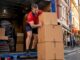 Mover loading boxes into removalist truck outside house