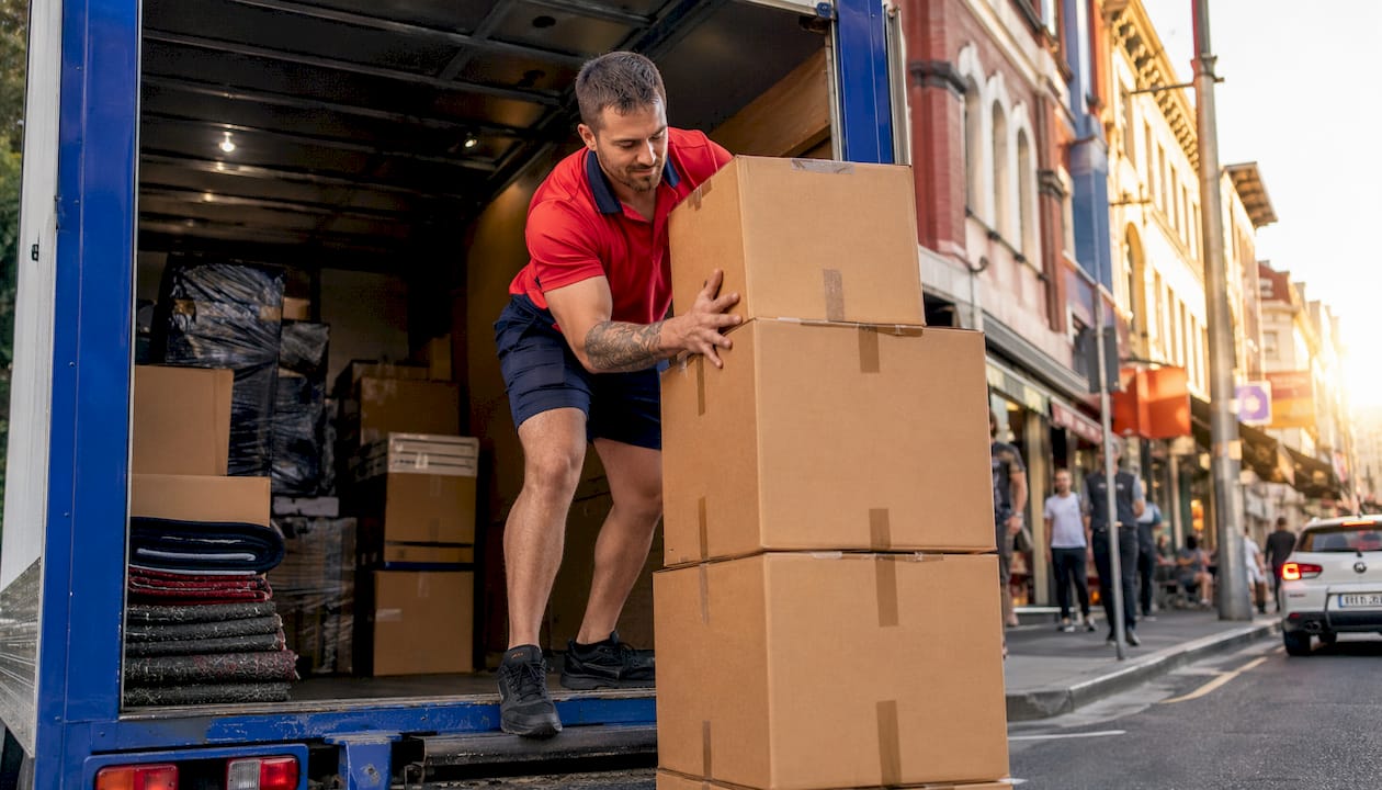 Mover loading boxes into removalist truck outside house
