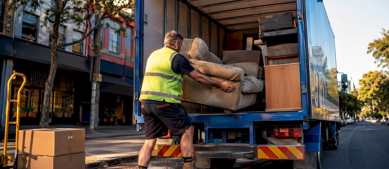 Worker loading sofa into furniture removal truck