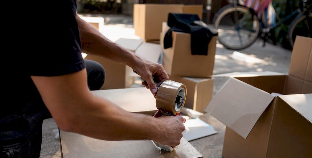 Hands taping moving boxes in garage