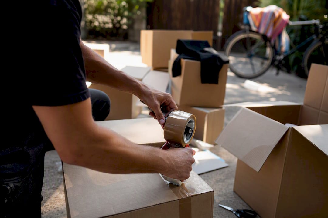 Hands taping moving boxes in garage