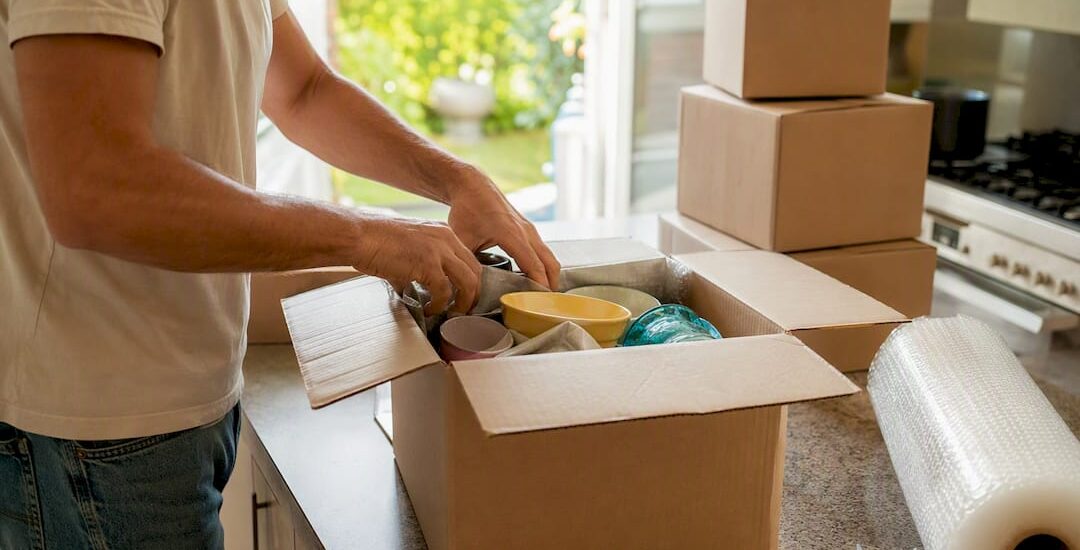 Hands packing moving box with household items