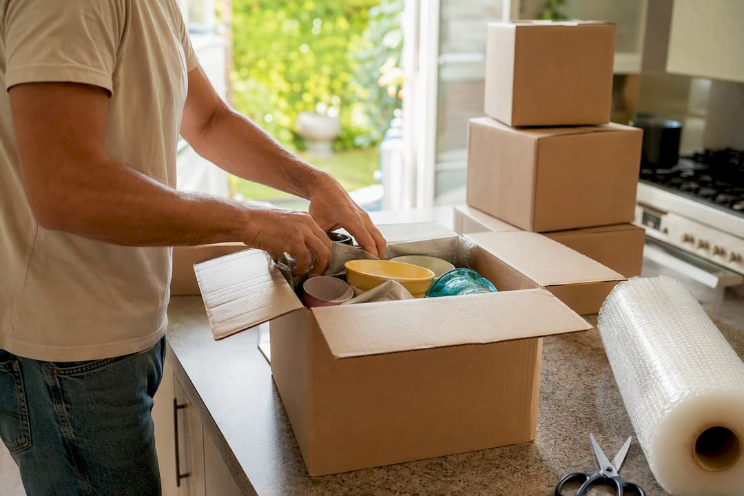 Hands packing moving box with household items