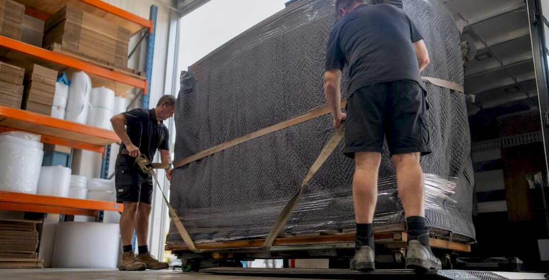 Movers securing oversized item on truck