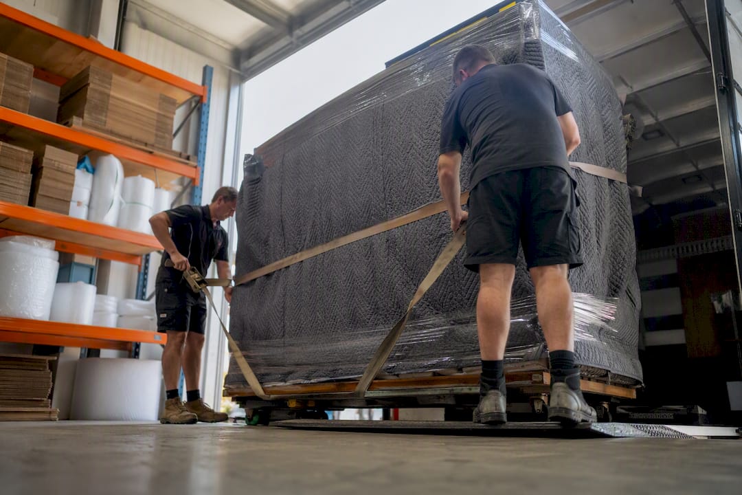 Movers securing oversized item on truck
