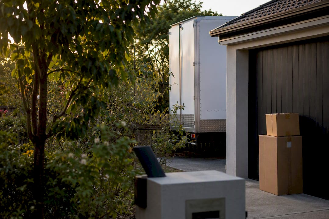 Moving truck corner and packed boxes in driveway