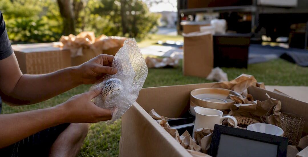 Hands packing fragile items on porch