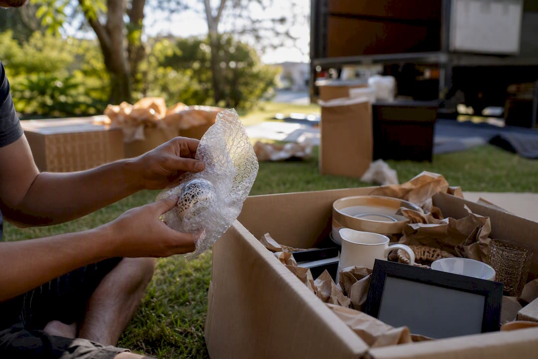 Hands packing fragile items on porch