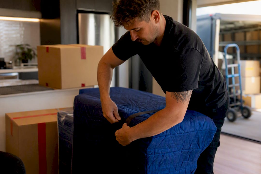 Mover carefully wrapping sofa in protective blanket