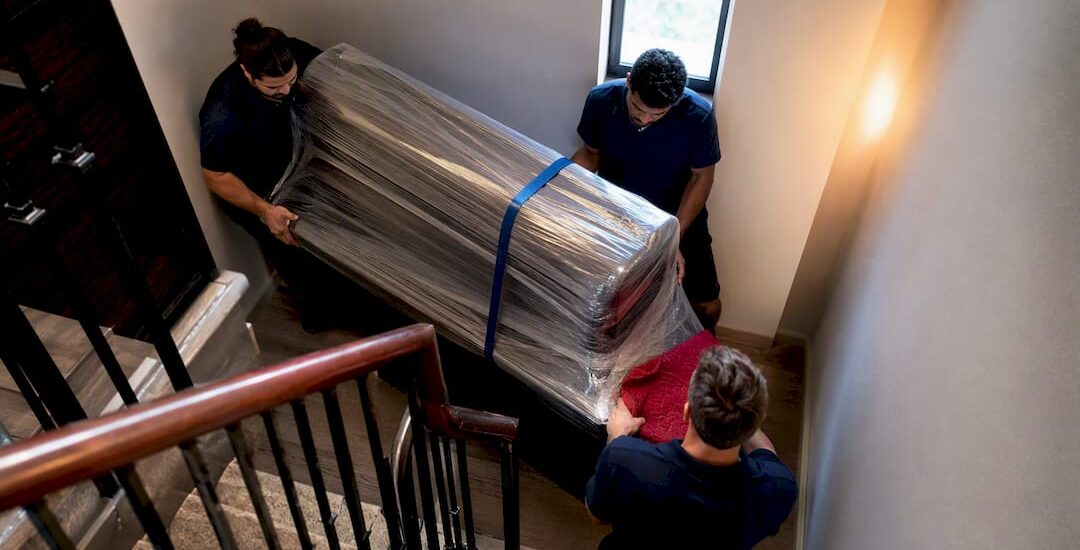 Wrapped piano carried through a tight stairwell