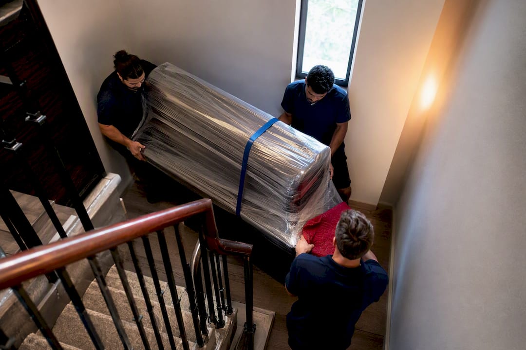 Wrapped piano carried through a tight stairwell