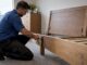 Removalist dismantling a wooden bed frame
