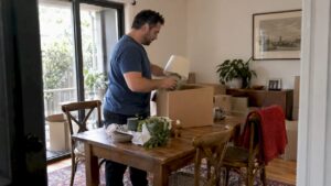 Resident packing household items into a moving box